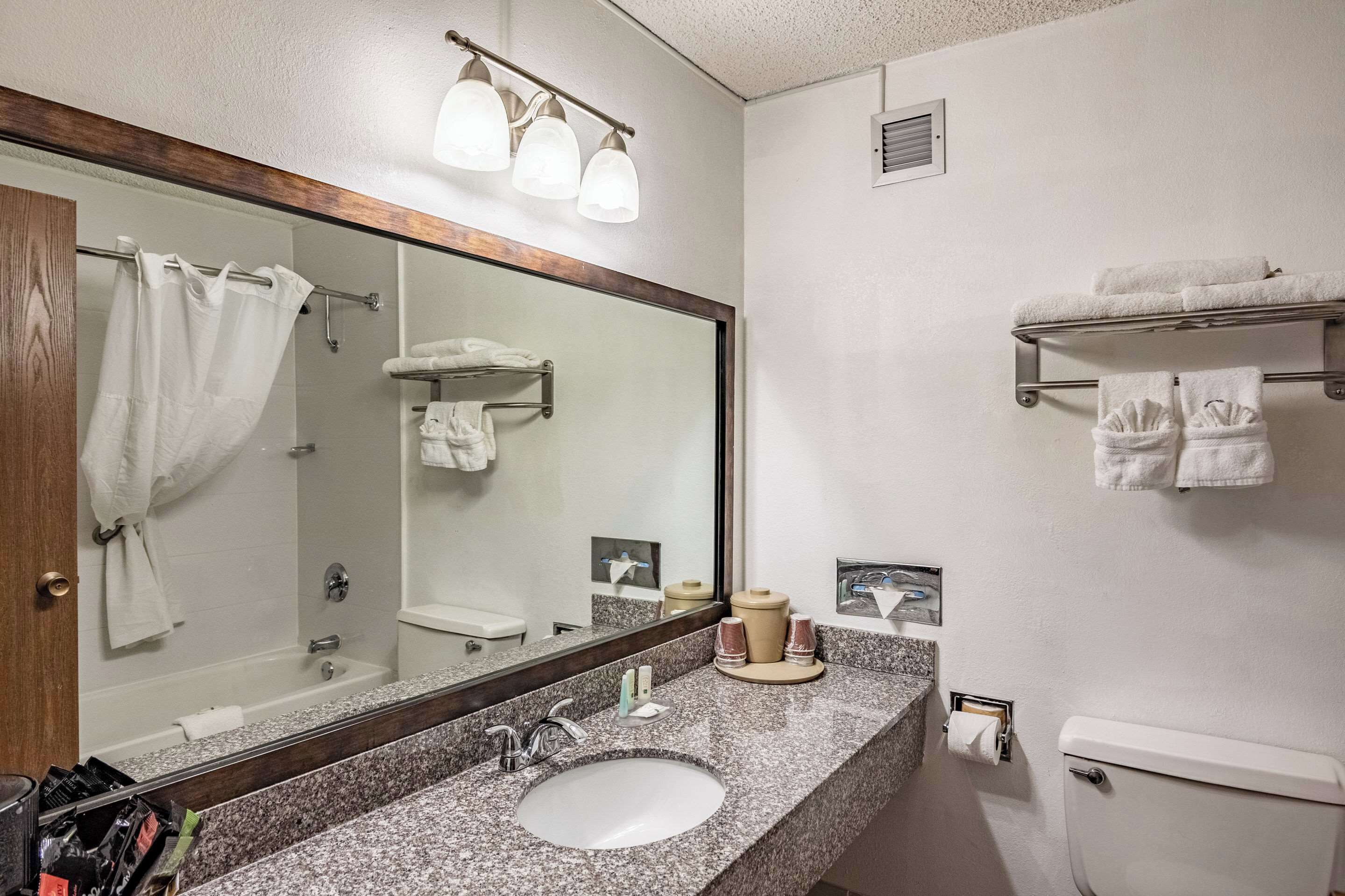 A bathroom with a sink, mirror, towel rack, and a toilet.