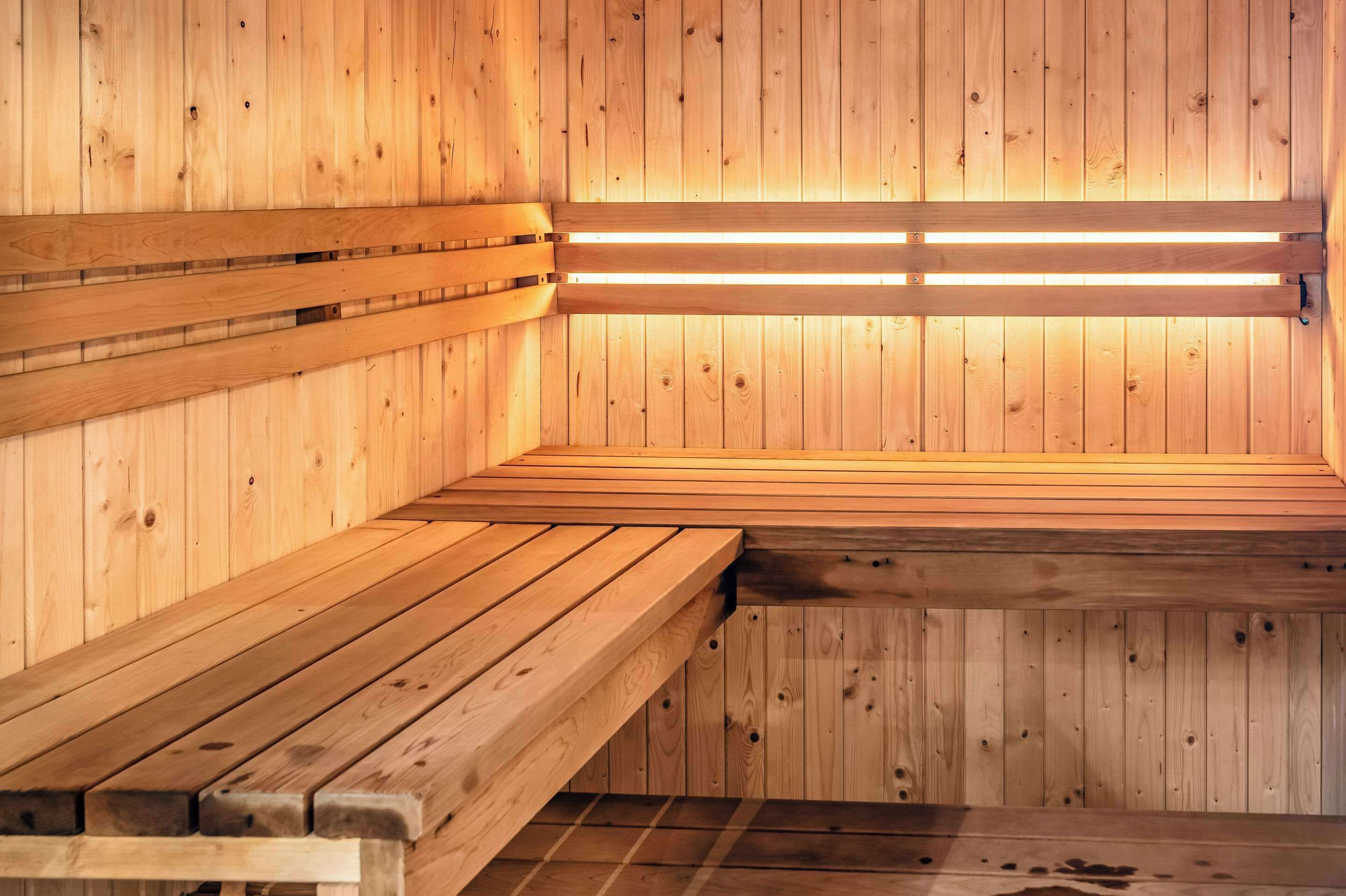 Una sauna con bancos y asientos de madera, paredes de madera y un techo con luminarias.