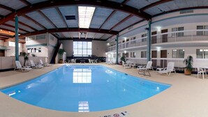 Une piscine intérieure dotée de chaises longues et d’un toit ouvrant.