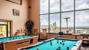 Une table de billard dans une pièce dotée de grandes fenêtres donnant sur un paysage magnifique.