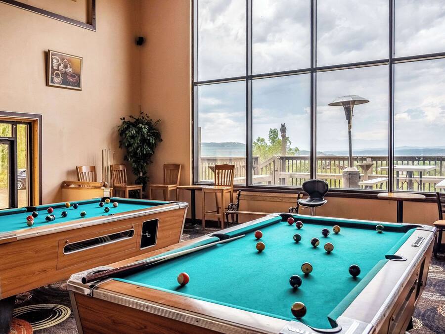 A pool table in a room with large windows overlooking a scenic view.