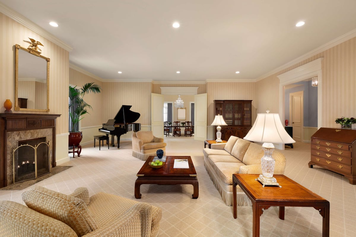 A spacious living room with a fireplace, a grand piano, and a comfortable sofa set.