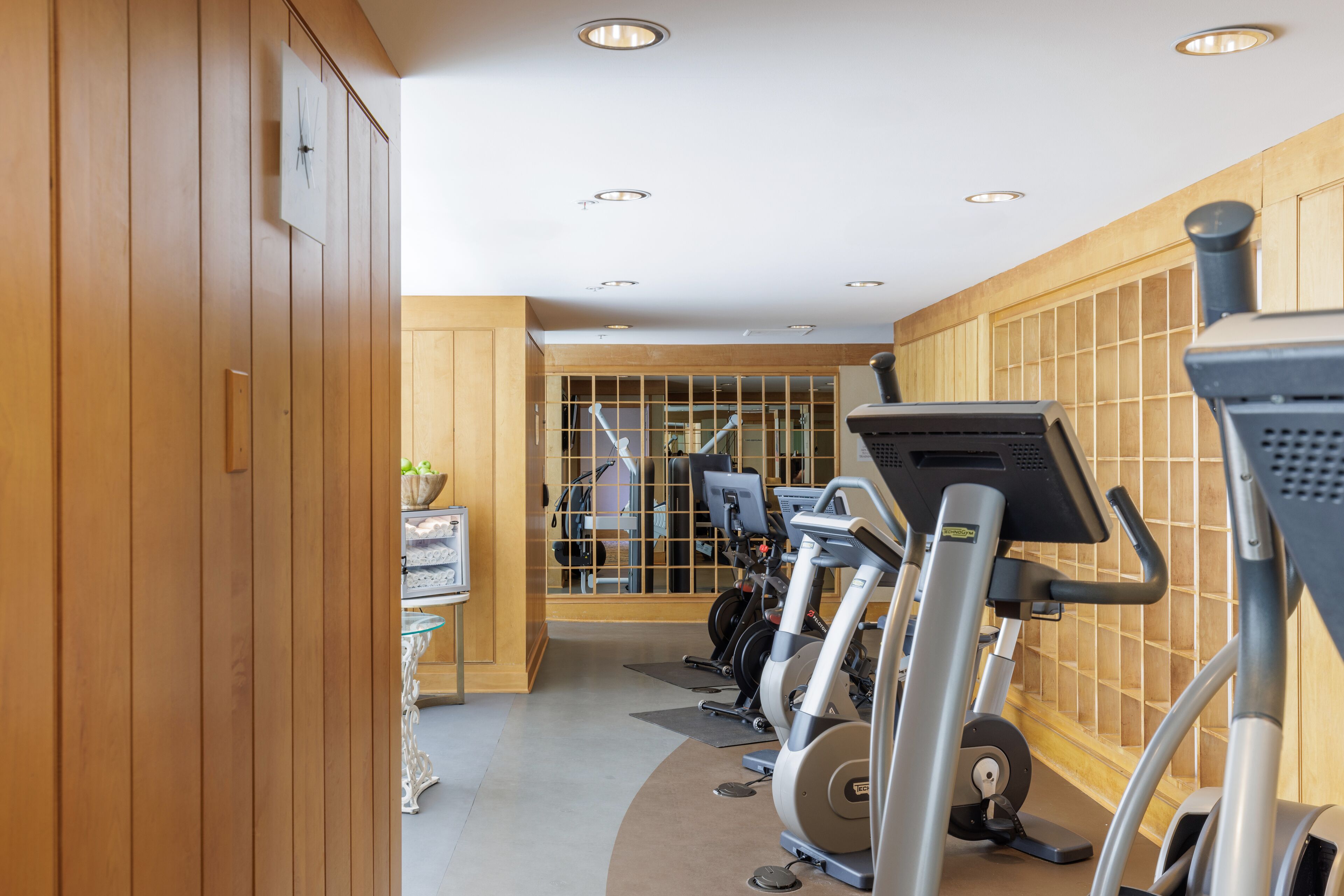 A gym with exercise equipment, wooden walls, and a mirrored wall.
