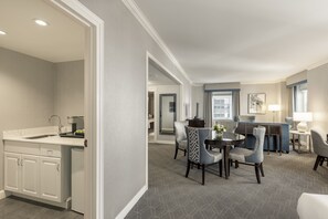 A modern kitchen with white cabinetry, a built-in sink, and a dining area with a round table and chairs.