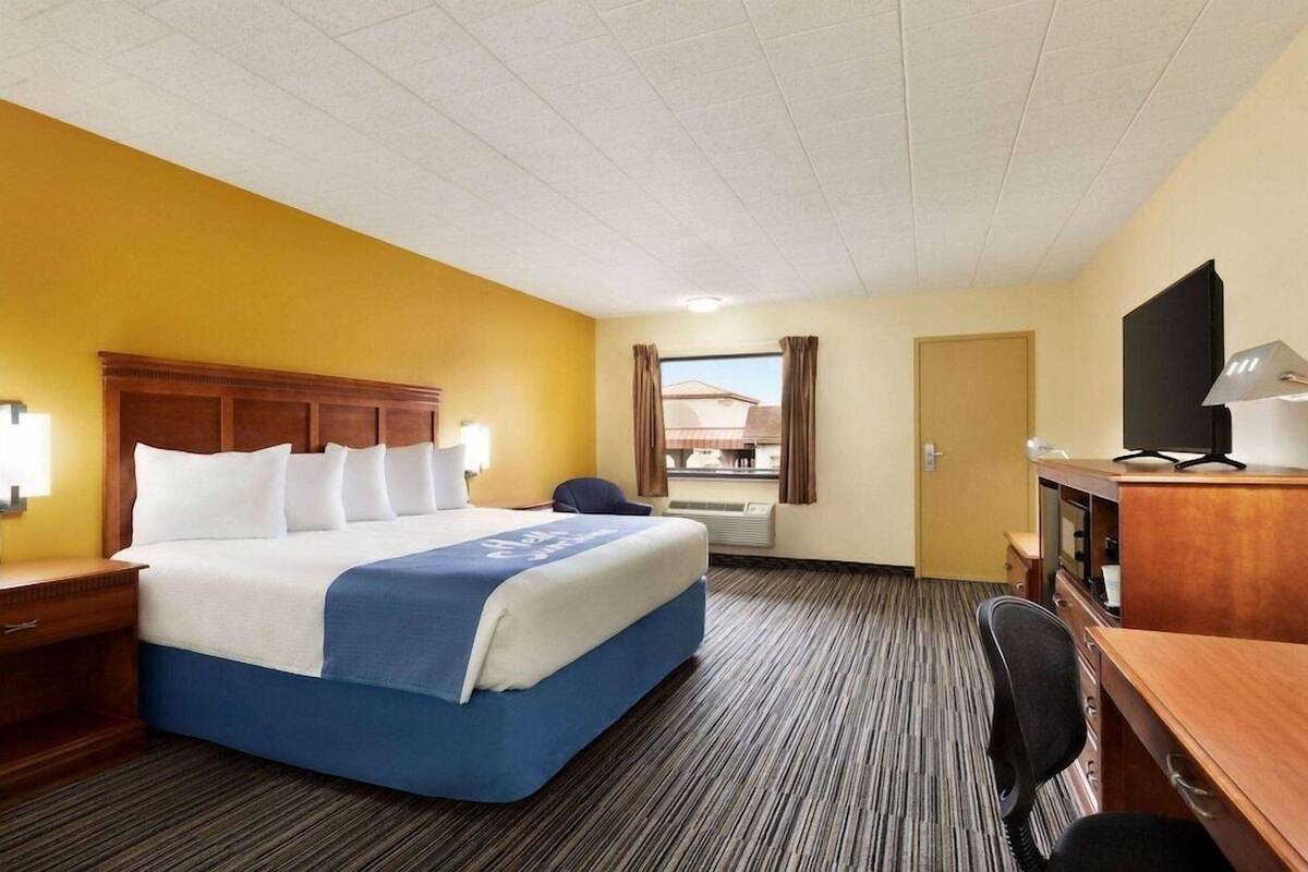 Una habitación de hotel con cama, escritorio, silla y televisor.