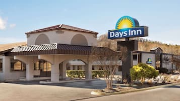 A Days Inn with a prominent sign, a covered parking area, and a building with a flat roof and arched windows.