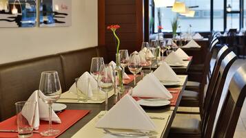 A restaurant with a long table set for dining, featuring neatly arranged plates, glasses, and napkins.