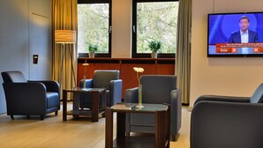 A modern hotel room with two large windows, a flat-screen TV, and a seating area with two armchairs and a coffee table. - Michel Hotel Wetzlar (Wetzlar)