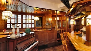 A bar area with a piano, wooden bar counter, and seating. - Michel Hotel Wetzlar (Wetzlar)