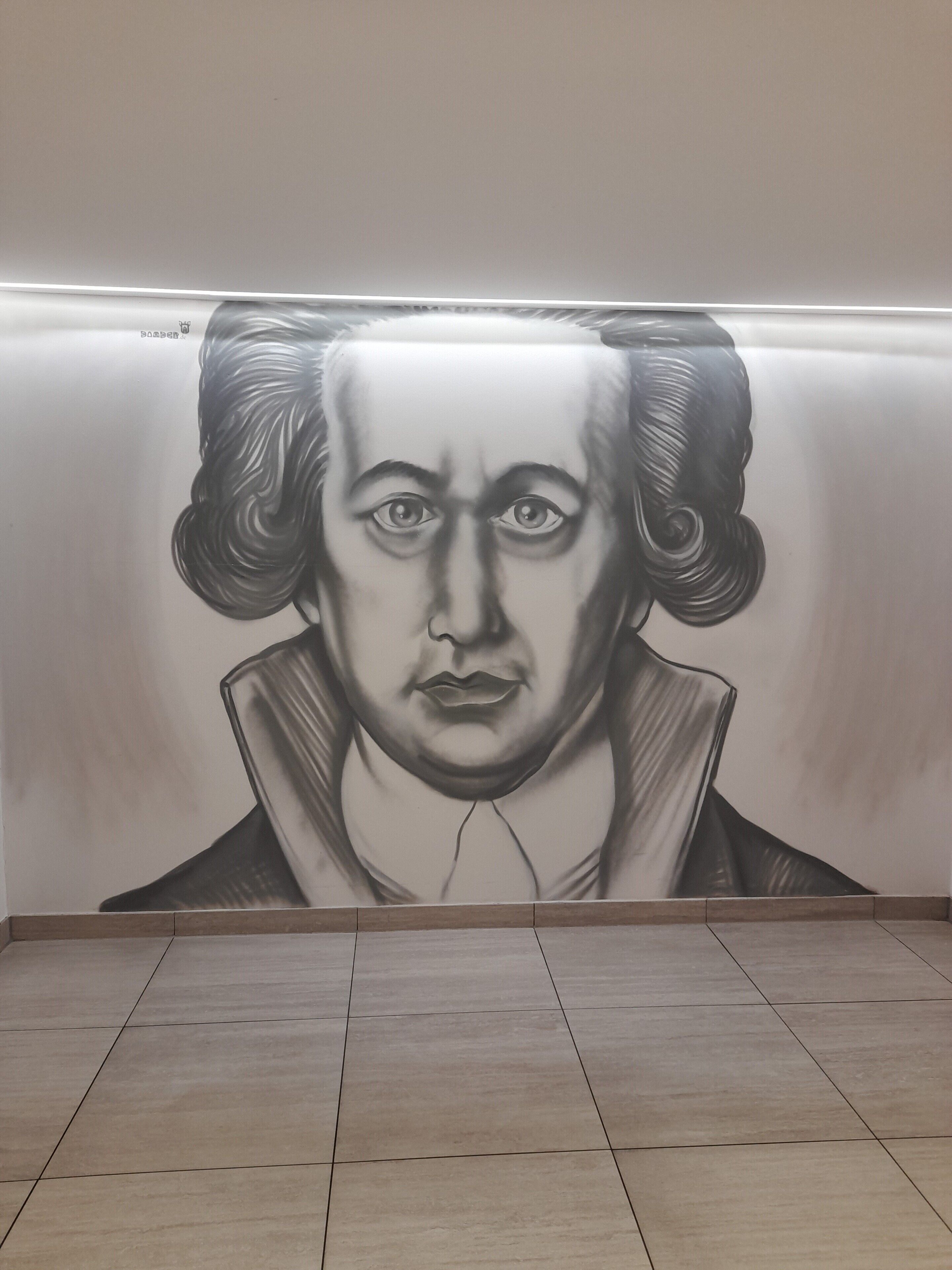 Een muur met een grote, gedetailleerde muurschildering van een persoon.