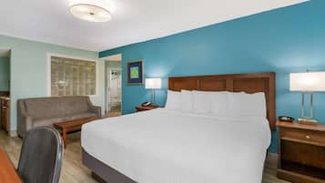 A hotel room with a large bed, a sofa, a desk, and a chair.
