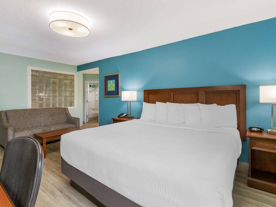 A hotel room with a large bed, a sofa, a desk, and a chair.