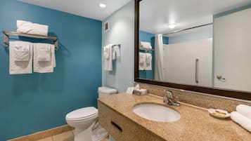 A bathroom with a blue wall, white toilet, and sink with a mirror above it.