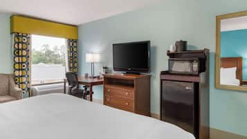 A hotel room with a bed, a desk, a television, a microwave, and a chair.