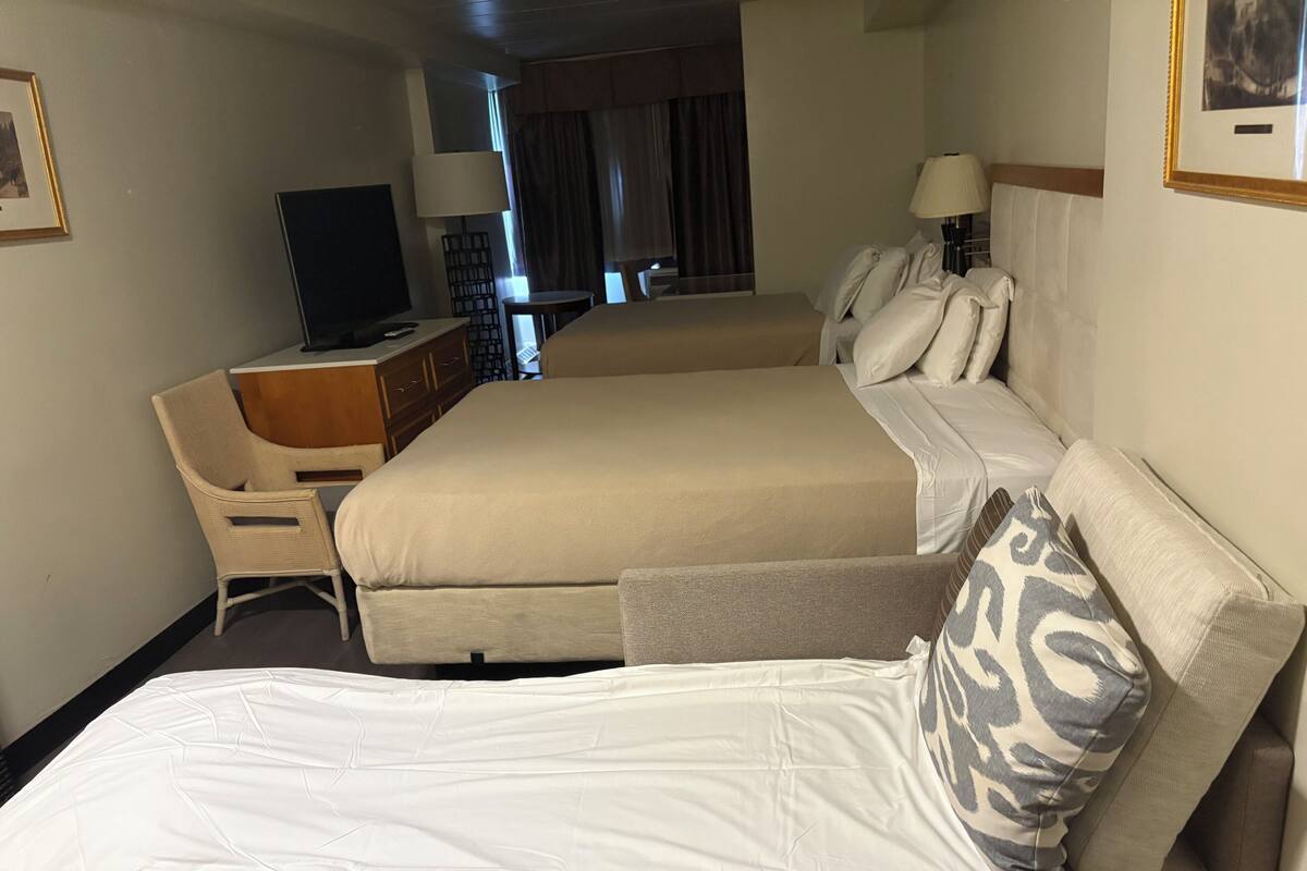 Une chambre d’hôtel avec deux lits, un bureau, une télévision et une lampe.