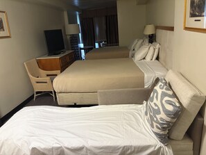 Ein Hotelzimmer mit zwei Betten, einem Schreibtisch, einem Fernseher und einer Lampe.