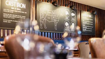 A restaurant interior with wooden paneling, a chalkboard menu, and a bar area.