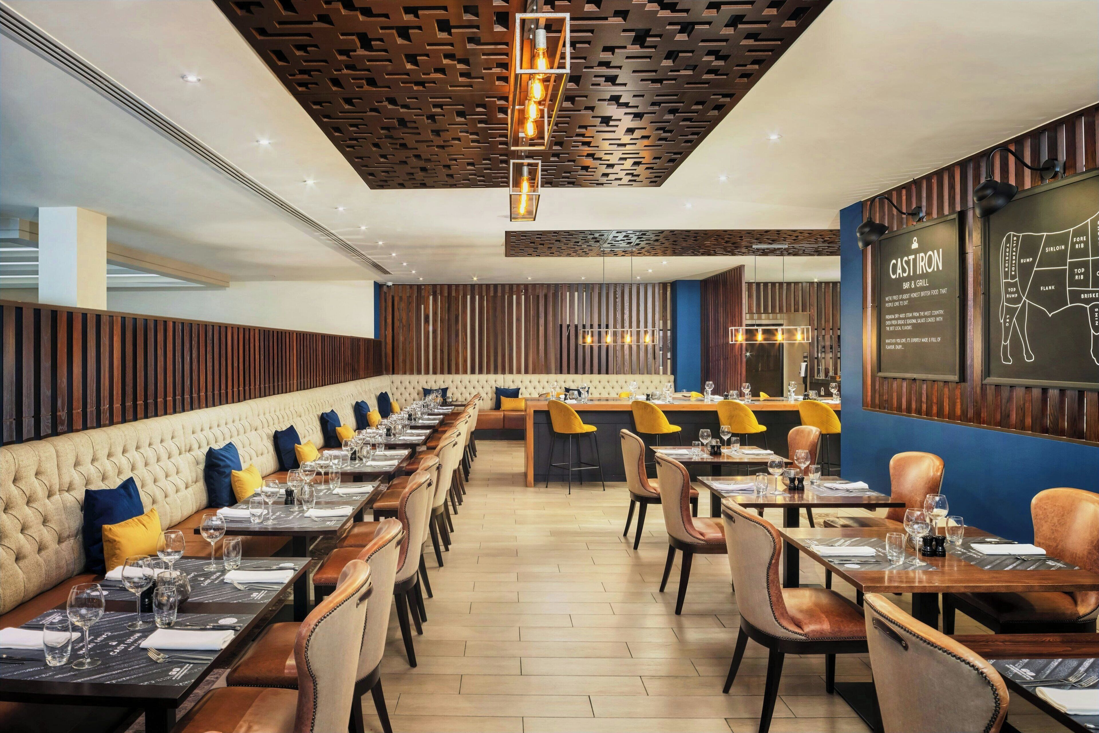 A restaurant with a long counter, booths, and a bar area.