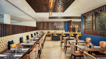 A restaurant with a long counter, booths, and a bar area.