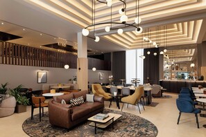 A modern hotel lobby with a central seating area, a bar, and a high ceiling with unique lighting fixtures. - Sheraton Heathrow Hotel (West Drayton)