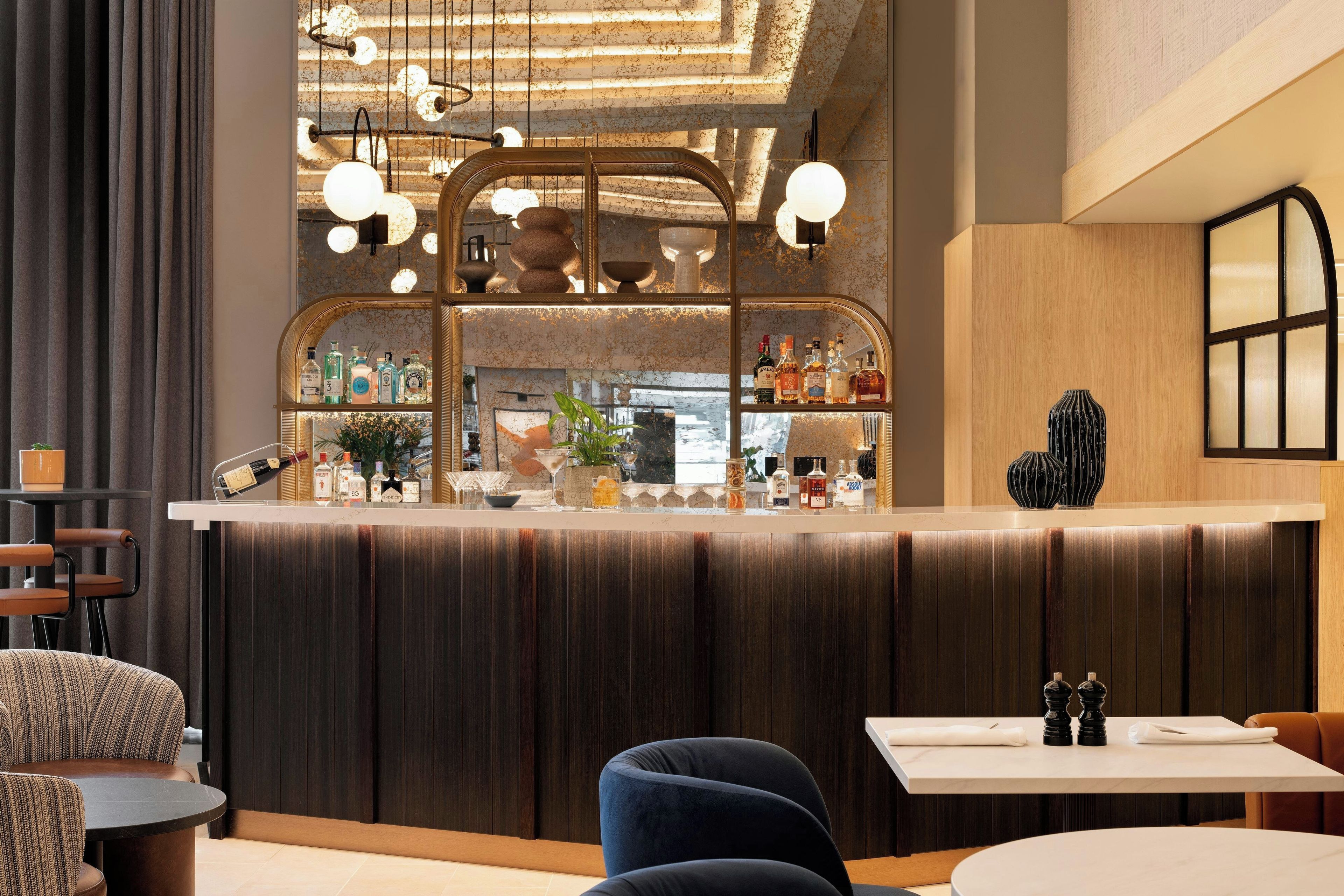 Een bar met een houten toonbank, zitplaatsen en een decoratief plafond.