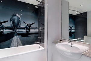 Un baño moderno con un espejo grande, un lavamanos blanco y una bañera.