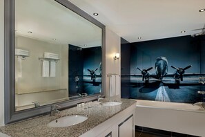 A modern bathroom with two sinks, a large mirror, and a wall-mounted towel rack.