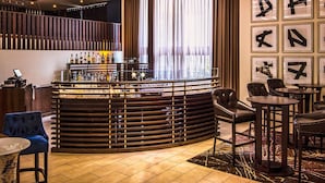 A bar area with a modern chandelier, a bar counter with bottles, and seating arrangements.
