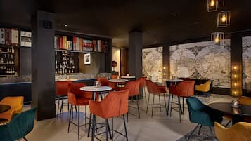 A modern bar area with red and teal chairs, a bar counter with bottles, and a large world map on the wall.