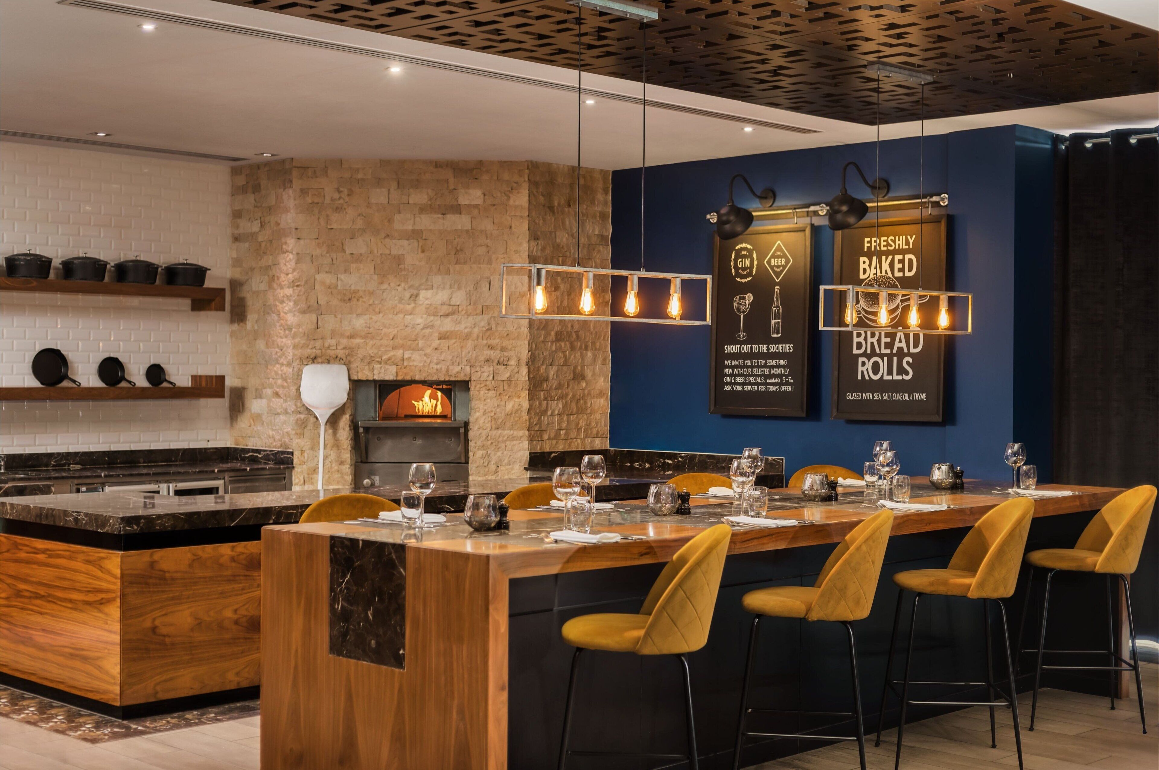 Een moderne keuken met een centraal eiland, een stenen muur en hangende pendelverlichting.