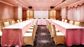 A conference room with a long table, chairs, a projector screen, and a carpeted floor. - Golden China Hotel (Taipei)