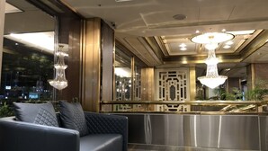 A modern lobby with a sofa, chandeliers, and a decorative reception desk. - Golden China Hotel (Taipei)