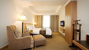 A hotel room with a bed, a sofa, a TV, and a desk. - Golden China Hotel (Taipei)