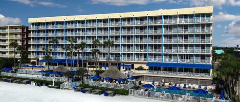 Un hotel de varios pisos con balcones, zona de piscina y vistas a la playa.