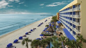 Ein Hotel direkt am Strand mit Pool, Liegestühlen und Sonnenschirmen.