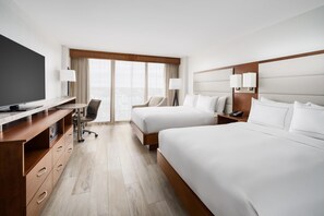 A hotel room with a TV, desk, two beds, a chair, and a view of the city. - DoubleTree Beach Resort by Hilton Tampa Bay - North Redingto (North Redington Beach)