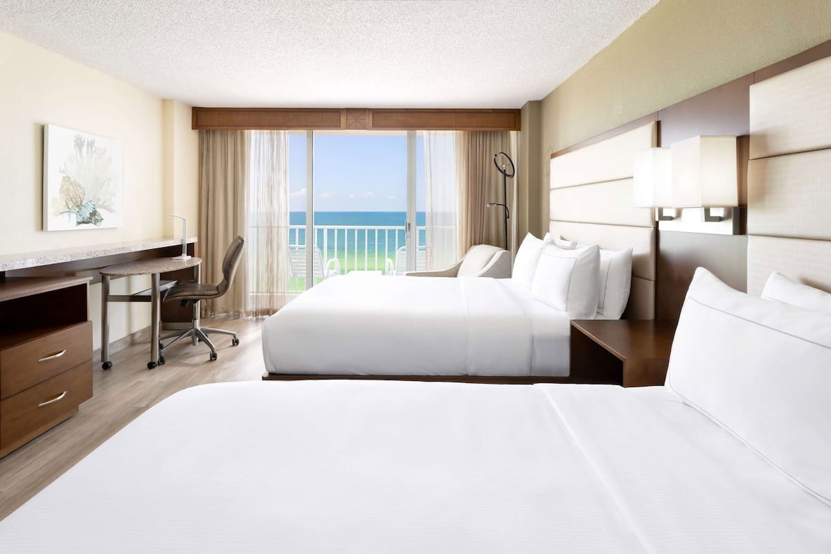 A hotel room with a large bed, a desk, and a view of the ocean.