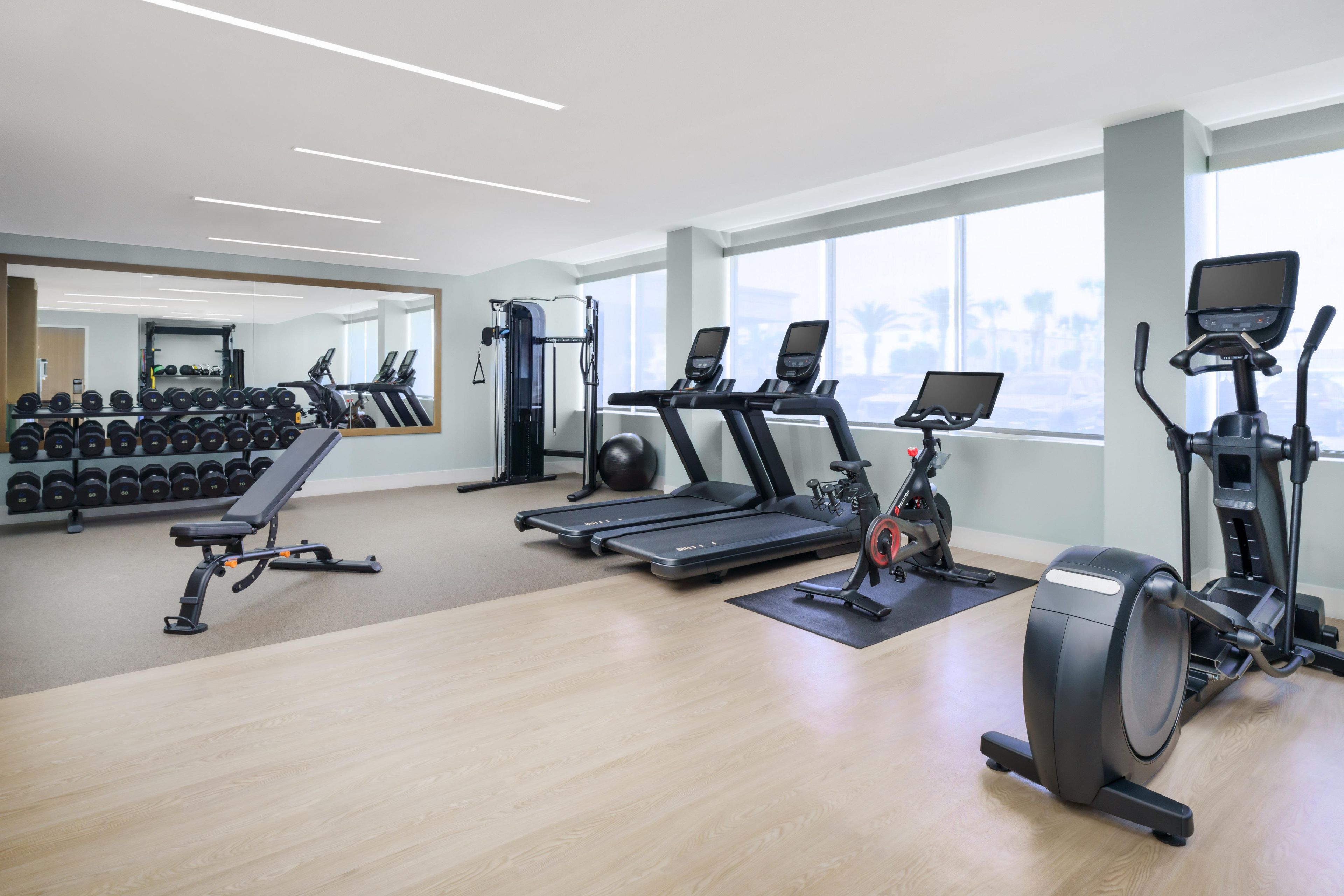 Un gimnasio con cintas de correr, elípticas y pesas sueltas.