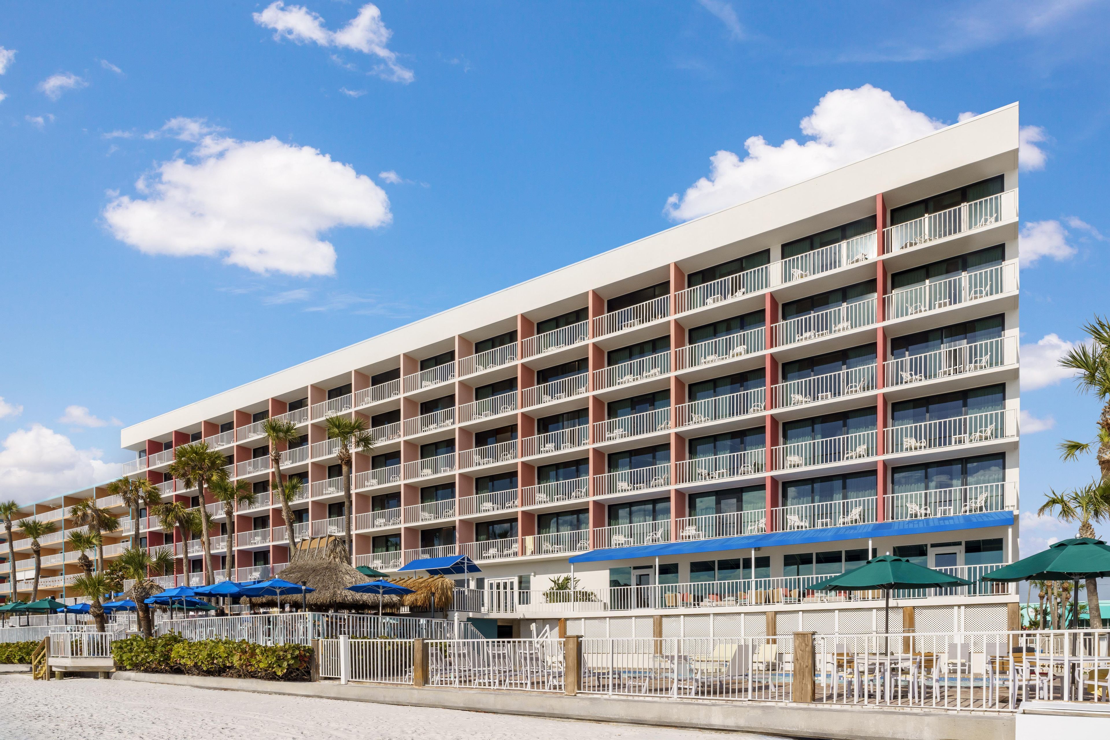 A multi-story hotel with balconies, a pool area, and outdoor seating.