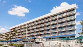 A multi-story hotel with balconies, a pool area, and outdoor seating.