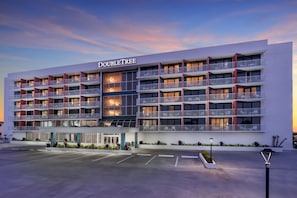 A multi-story hotel with a modern facade, named 'DOUBLETREE,' featuring balconies with seating and a parking lot in front. - DoubleTree Beach Resort by Hilton Tampa Bay - North Redingto (North Redington Beach)