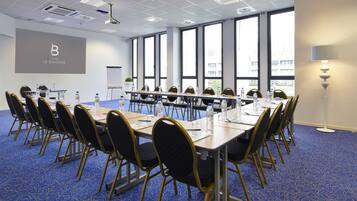 A conference room with a long table, chairs, water bottles, and a projector screen.