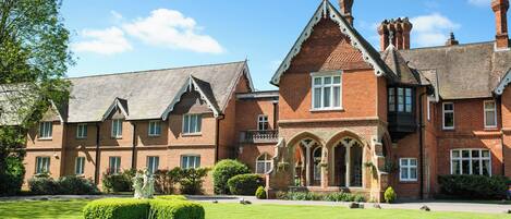 A large brick building with multiple windows and a well-maintained lawn.