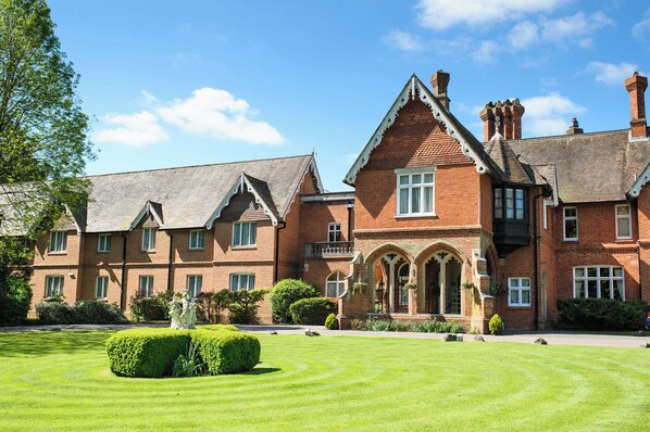 A large brick building with multiple windows and a well-maintained lawn. - Audleys Wood Hotel (Basingstoke)