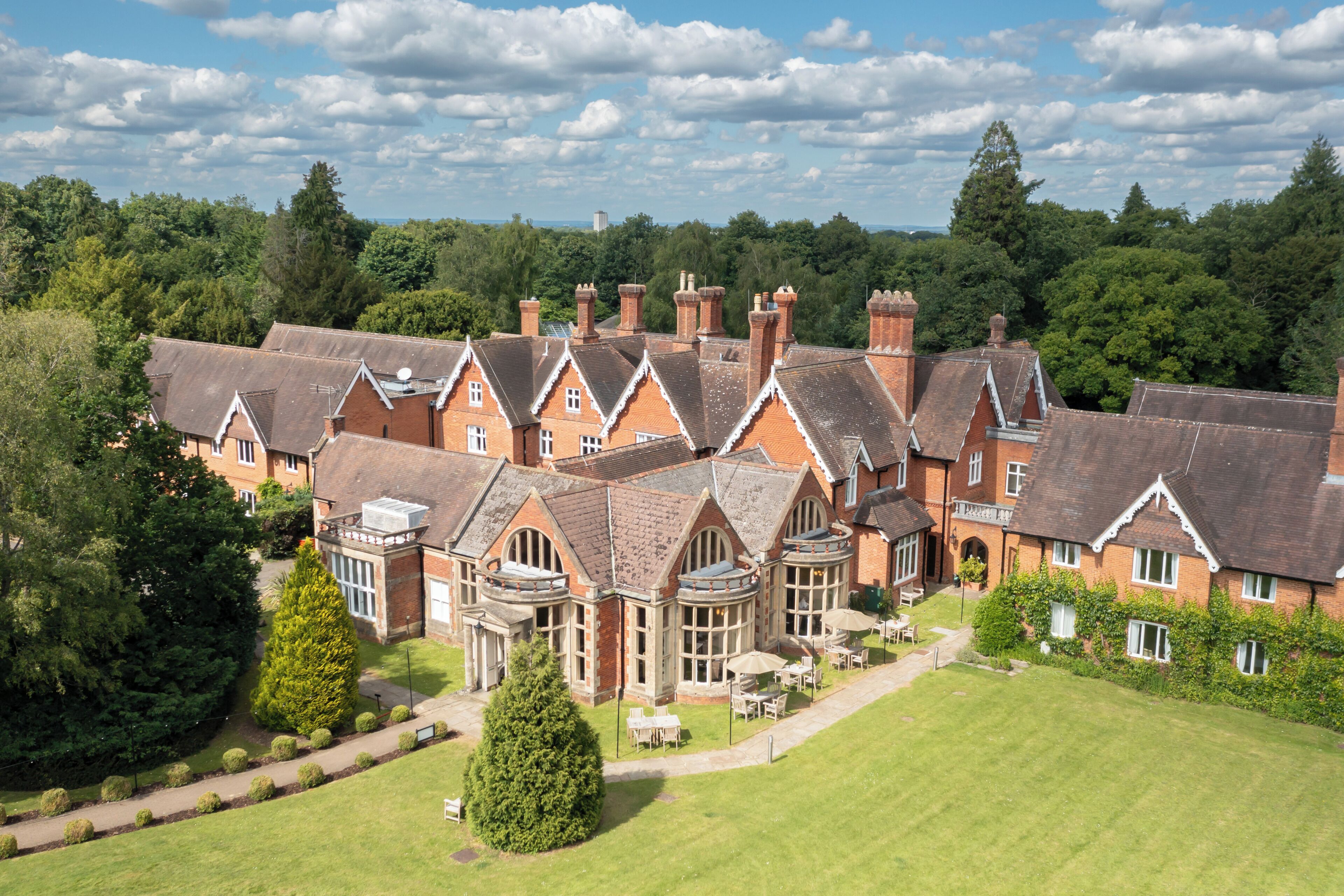 Un grande edificio in mattoni dal design tradizionale, con diversi camini e un prato curato.