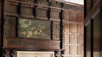 A dining room with a fireplace, ornate wood paneling, and a chandelier.