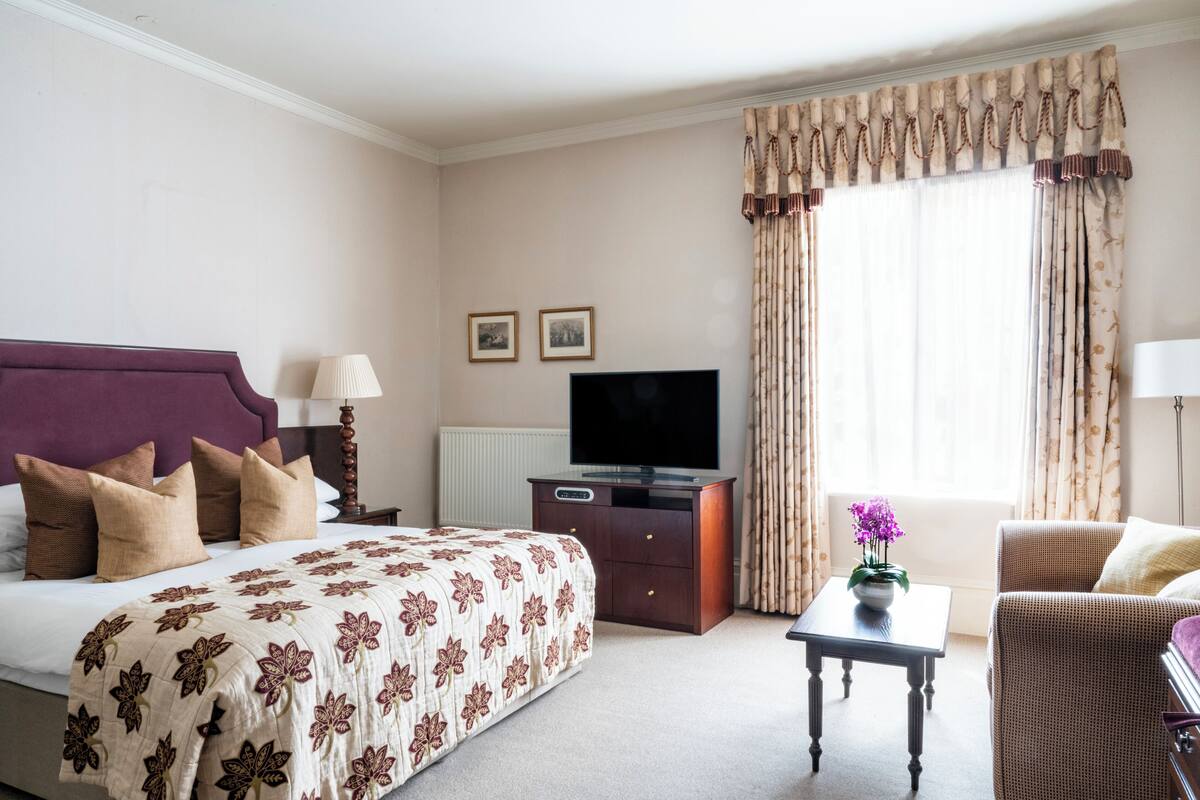 A hotel room with a bed, a TV, a desk, and a chair.