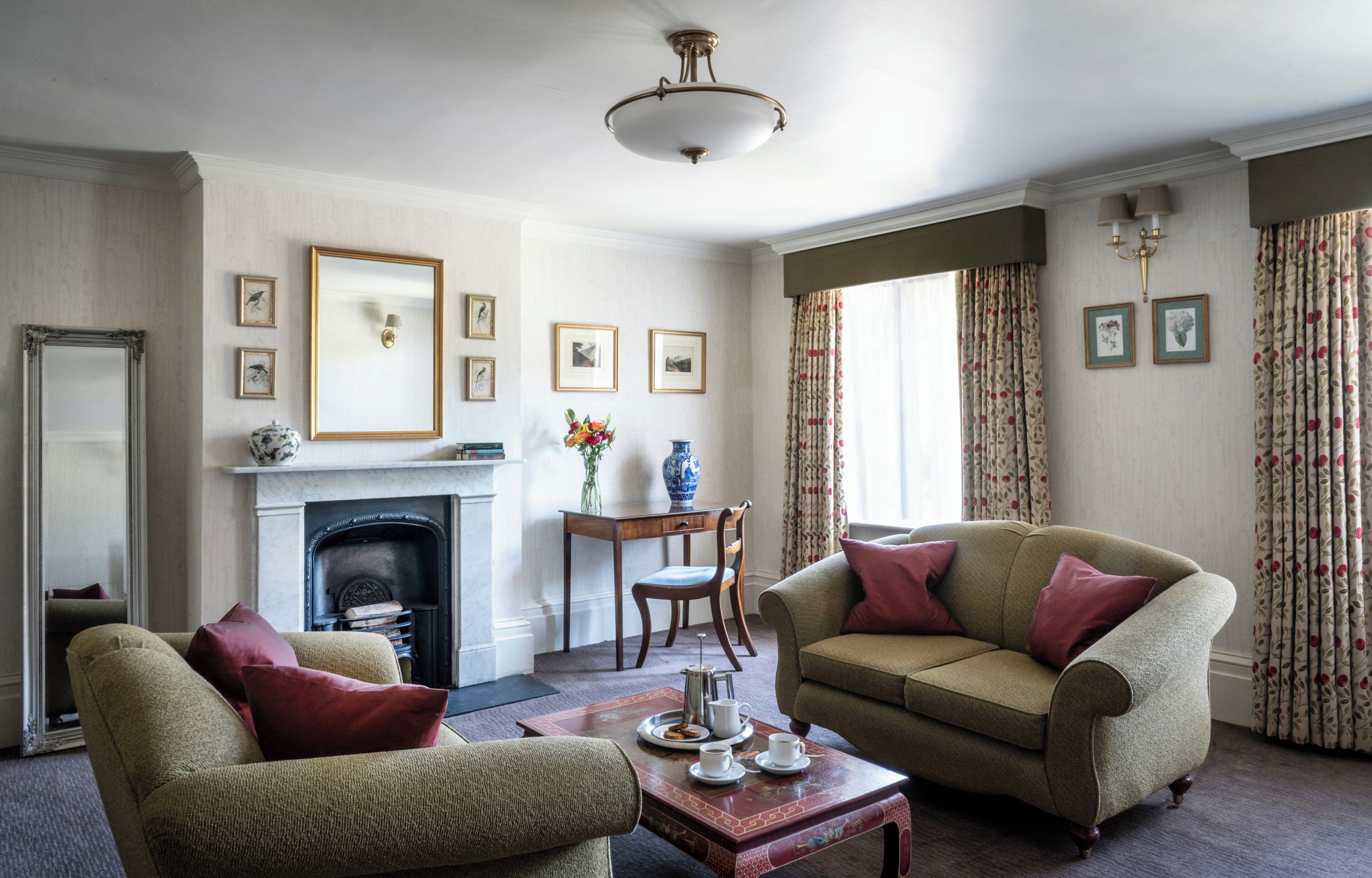 A traditional living room with a fireplace, two sofas, a coffee table, and a mirror.