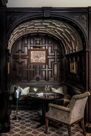 A dark wood-paneled room with a round table, a chair, and a framed picture on the wall. - Audleys Wood Hotel (Basingstoke)