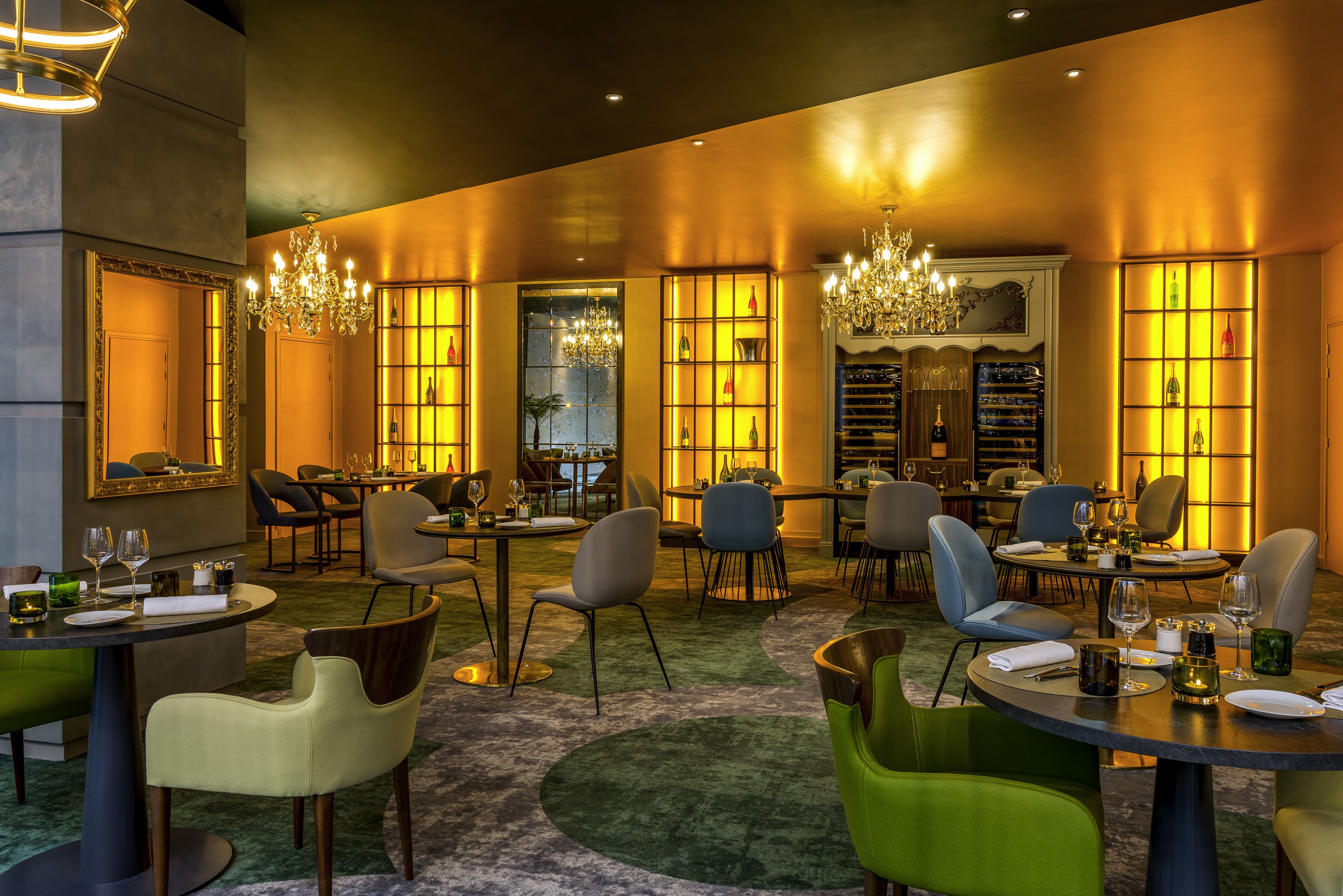 Un restaurante con varias mesas y sillas, candelabros y un ambiente cálido.